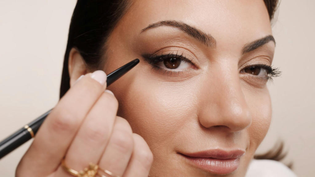 Katia Mosally in a close-up photo,she's applying eyeliner to her eyelid.